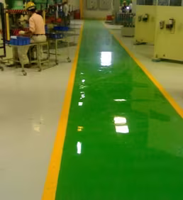 Üretim alanında uygulanan epoksi zemin kaplama ile iş güvenliği çizgileri belirlenmiş, parlak ve dayanıklı endüstriyel zemin