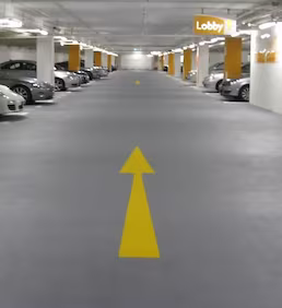 Kapalı otoparkta epoksi zemin kaplama ve yönlendirme oklarıyla güvenli ve dayanıklı yüzey oluşturulması